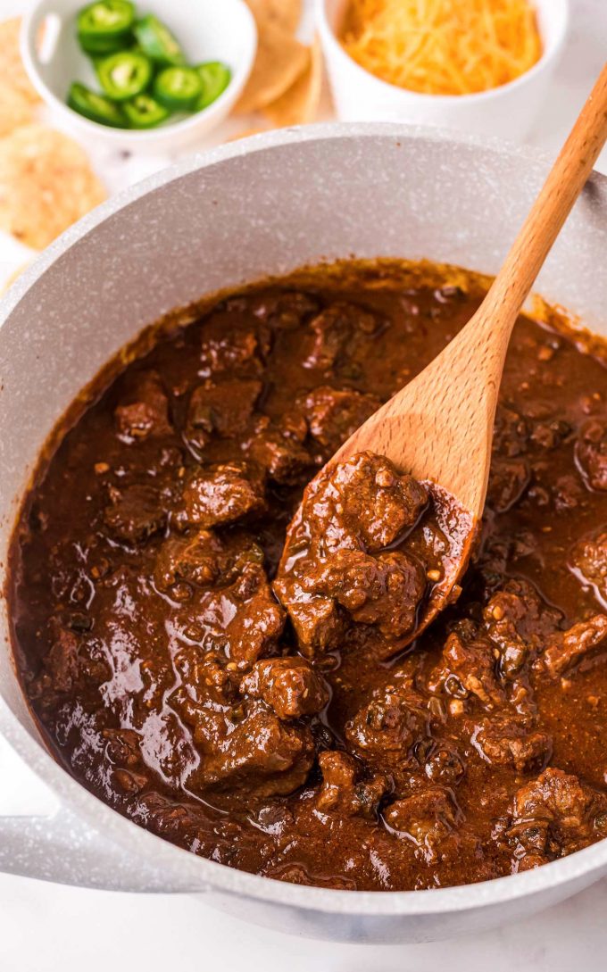 Stirring beef chili with wooden spoon