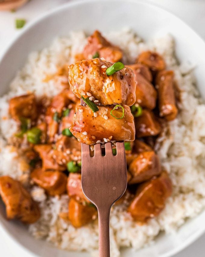 two pieces of chicken breasts in bourbon sauce on fork