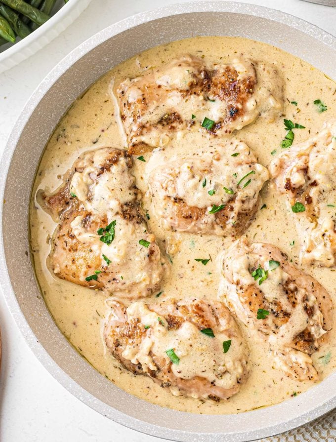 overhead view of chicken thighs in skillet with sauce
