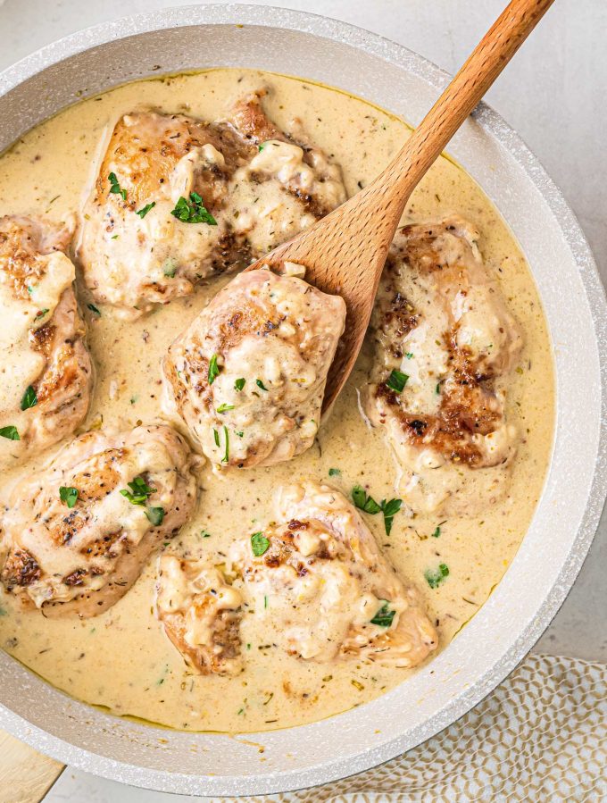 serving a chicken thigh in creamy sauce from skillet
