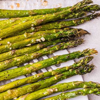 à l'aide d'une spatule pour ramasser les asperges grillées sur une plaque à pâtisserie