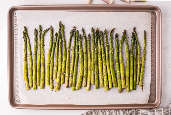 roasted asparagus spears lined up on baking sheet