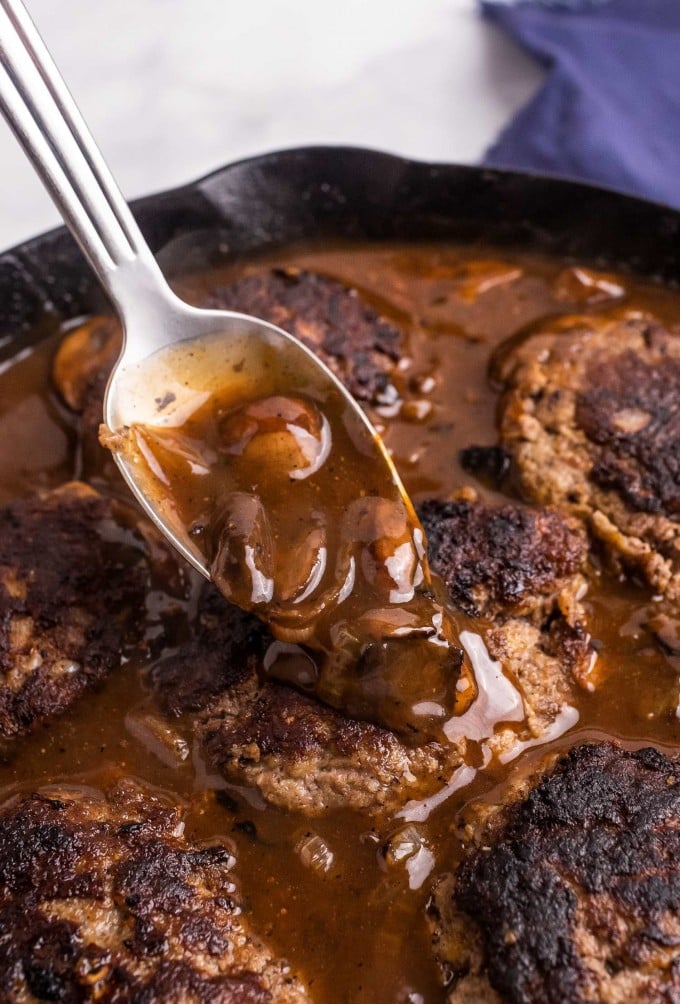 spooning mushroom onion gravy over salisbury steak patty