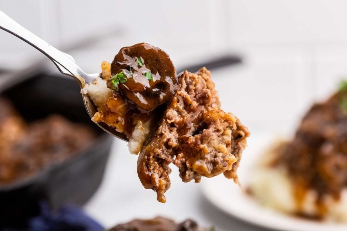 forkful of salisbury steak with mushrooms and mashed potatoes