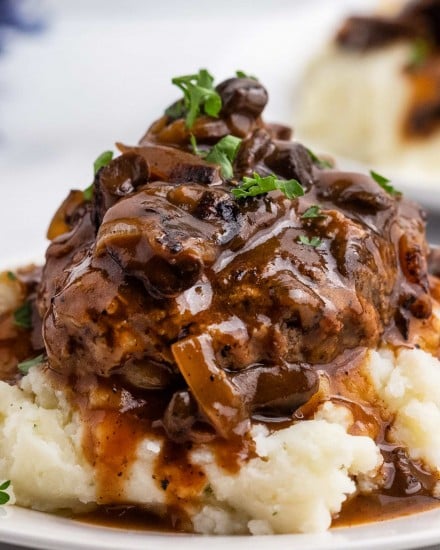 Salisbury Steak is an easy comfort food dinner that's reminiscent of tv dinners, but SO much better! Homemade ground beef steaks are smothered in the most amazing mushroom and onion gravy. It's a hearty one pan meal for the whole family. #salisburysteak #beef #groundbeef #dinner #dinnerrecipe #onepan