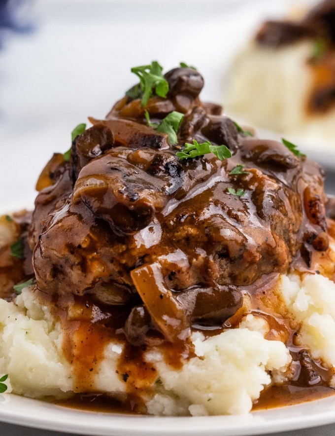 Salisbury Steak is an easy comfort food dinner that's reminiscent of tv dinners, but SO much better! Homemade ground beef steaks are smothered in the most amazing mushroom and onion gravy. It's a hearty one pan meal for the whole family. #salisburysteak #beef #groundbeef #dinner #dinnerrecipe #onepan