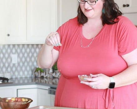 woman seasoning chicken on baking sheet