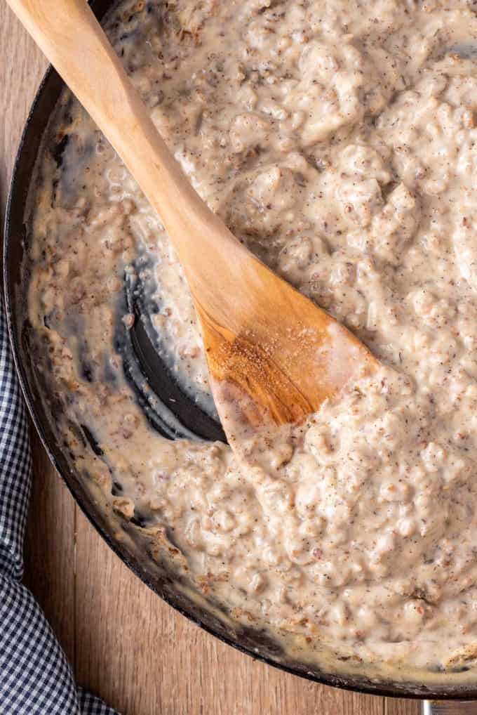 wooden spoon stirring sausage gravy in skillet