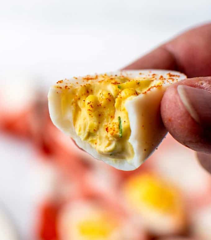 holding a deviled egg that's bitten in half