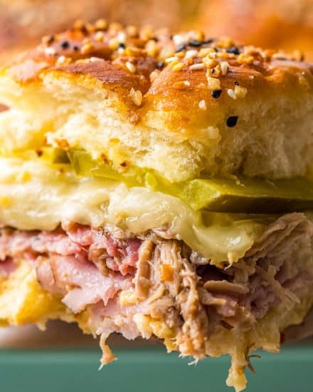 These Cuban Sliders are a fun appetizer version of the classic Cuban sandwich! Loaded with ham, pulled pork, mustard sauce, cheese and pickles, you'll love every bite of these delicious crowd-pleasing sliders. #sliders #cuban #ham #pork #appetizers #fingerfoods #partyfood