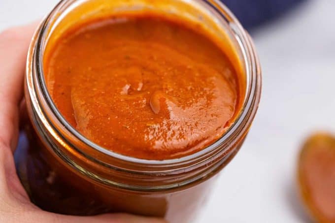 pouring enchilada sauce from a glass jar