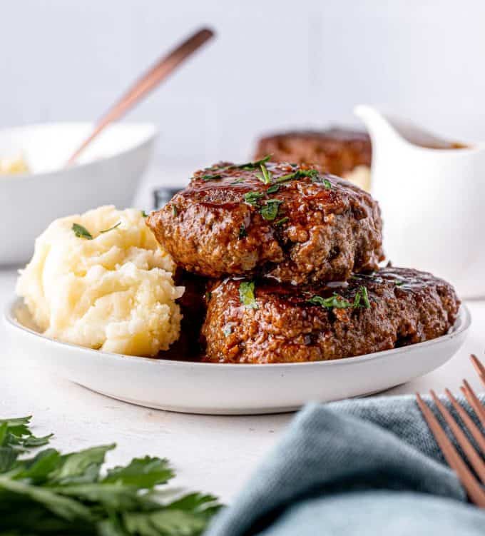 This fun take on classic salisbury steak is an easy comfort food dinner! Homemade ground beef steaks are smothered in the most amazing stout and onion bbq gravy. It's a hearty one pan meal for the whole family. #salisburysteak #beef #groundbeef #dinner #dinnerrecipe #onepan #stout #bbq #guinness