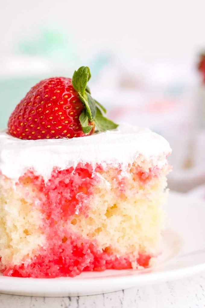 This Strawberry Poke Cake is the easiest and most delicious summer dessert around! Fluffy white cake is infused with strawberry jello, then slathered with whipped cream! Naturally a make ahead dessert, this is a dessert recipe the whole family will love! #pokecake #strawberrydessert #whitecake #dessert #baking #summerdessert