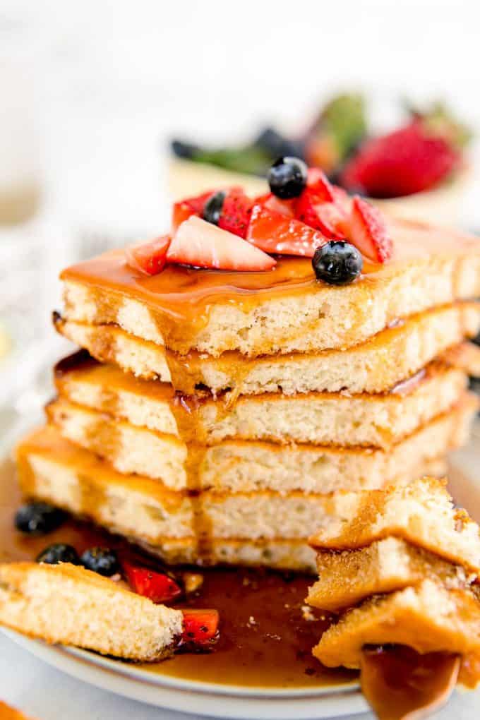 eating a stack of sheet pan pancakes with berries and syrup