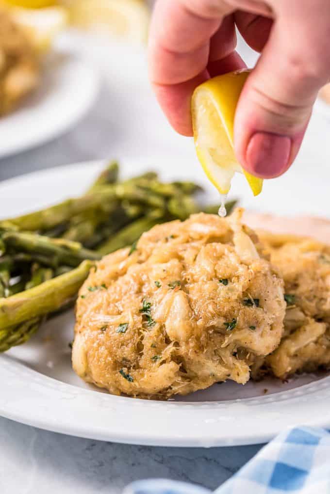 squeezing lemon over a crab cake