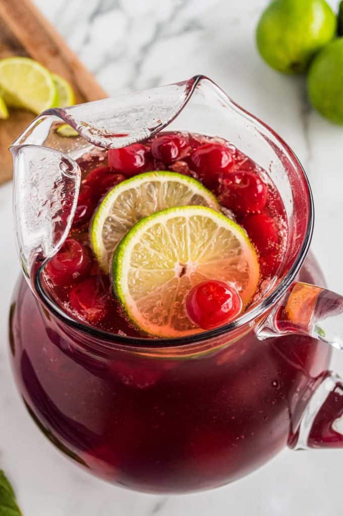 glass pitcher of cherry limeade with lime slices