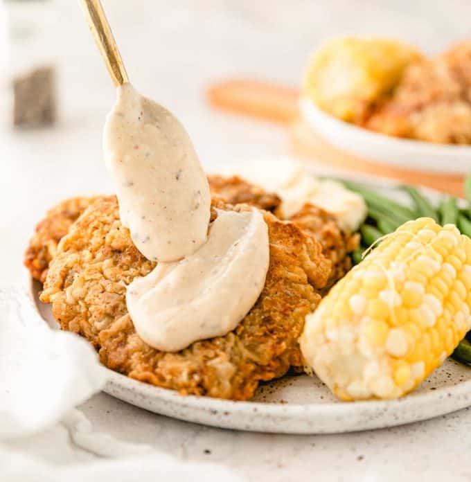 spooning pepper gravy onto chicken fried steak