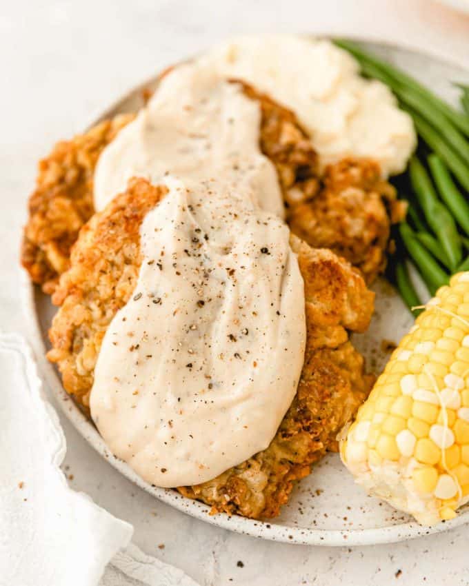 Chicken Fried Steak is a southern classic made with tender marinated cube steaks that have been breaded and pan fried until golden. And don't forget the creamy white pepper gravy on top! Restaurant-quality, but made easily at home. #chickenfriedsteak #beef #dinner #comfortfood