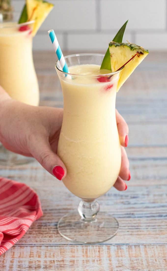 holding a glass of pina colada