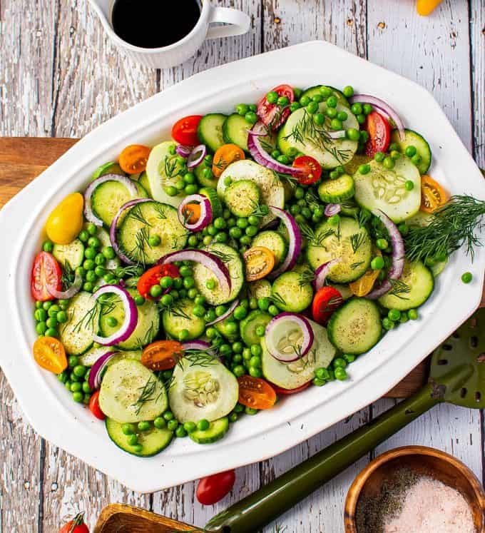 overhead view of cucumber salad on white platter.