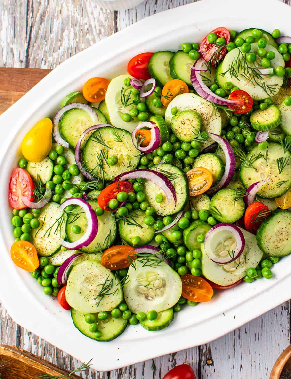 This easy mayo-free Cucumber Salad is complete with not only fresh cucumbers, but also sweet peas, crunchy red onion, tangy tomatoes, fresh herbs and a simple balsamic vinaigrette dressing. Perfect alongside a light summer meal or at a potluck! #cucumber #salad #summer