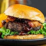 side view of homemade burger with bun on black plate