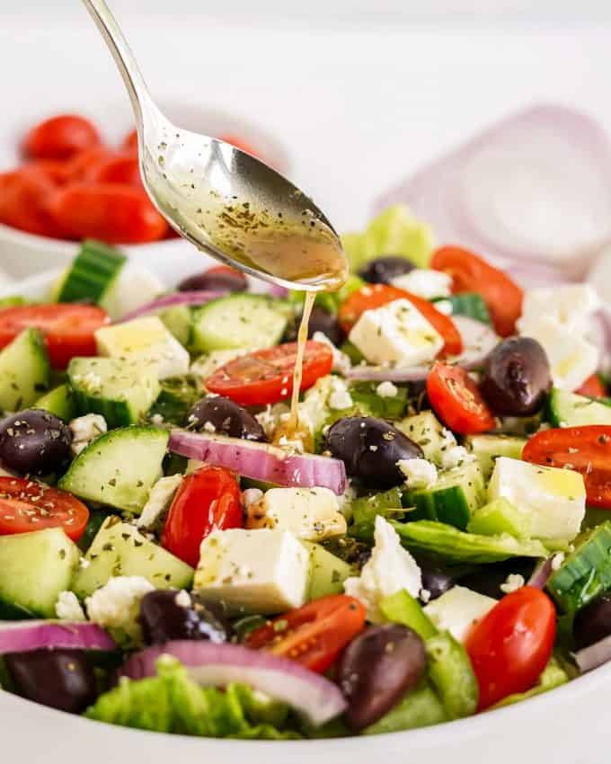 pouring Greek dressing over salad