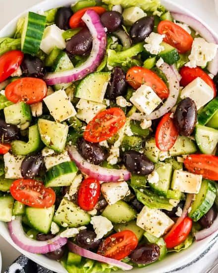 This perfect Greek salad comes together in just 10-15 minutes, and uses a homemade Greek dressing that's so much better than anything from a bottle. Perfect with lettuce or without, it's a delicious summer salad, and a great use for seasonal produce! #salad #greek #homemade