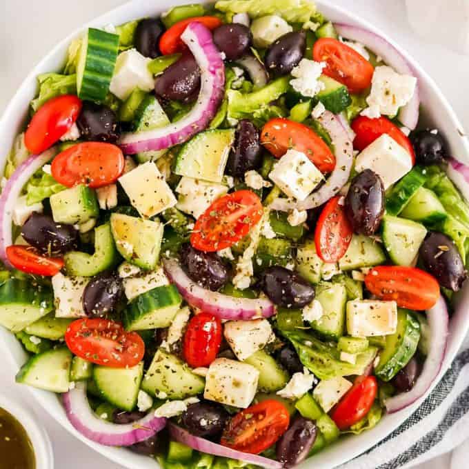 big greek salad in white bowl