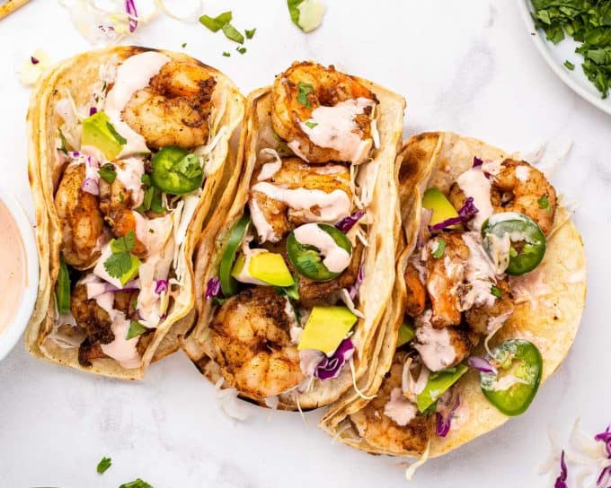 These Grilled Shrimp Tacos are smoky, a little spicy, and bursting with fresh flavors! The creamy sriracha lime sauce just takes them over the top. Easy to cook the shrimp indoors too! #tacos #shrimp #grilled