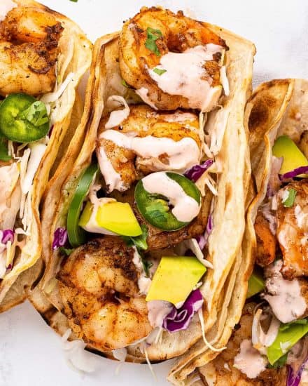 These Grilled Shrimp Tacos are smoky, a little spicy, and bursting with fresh flavors! The creamy sriracha lime sauce just takes them over the top. Easy to cook the shrimp indoors too! #tacos #shrimp #grilled