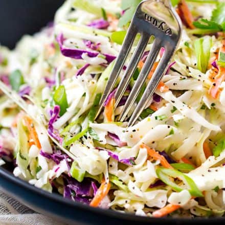 tequila lime coleslaw in black bowl with a fork.