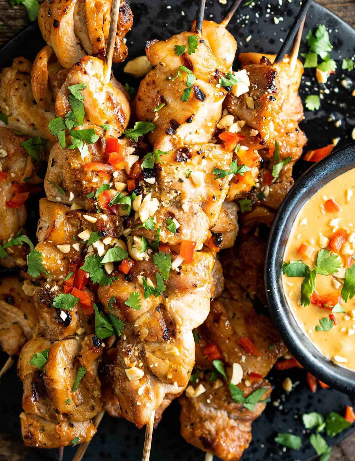 Juicy chicken thighs are marinated in an easy Thai-flavored marinade, then skewered and grilled until a little charred. And of course, don't forget the spicy peanut sauce that you'll be wanting to put on absolutely everything! #chickensatay #thai #peanutsauce #grilled