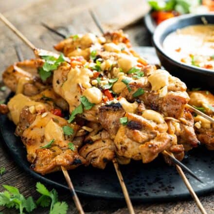 pile of chicken satay skewers on black plate