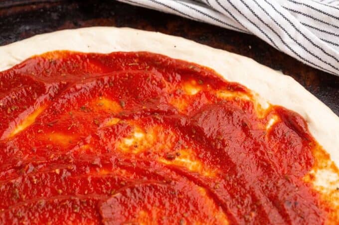 pizza sauce spread onto pizza dough