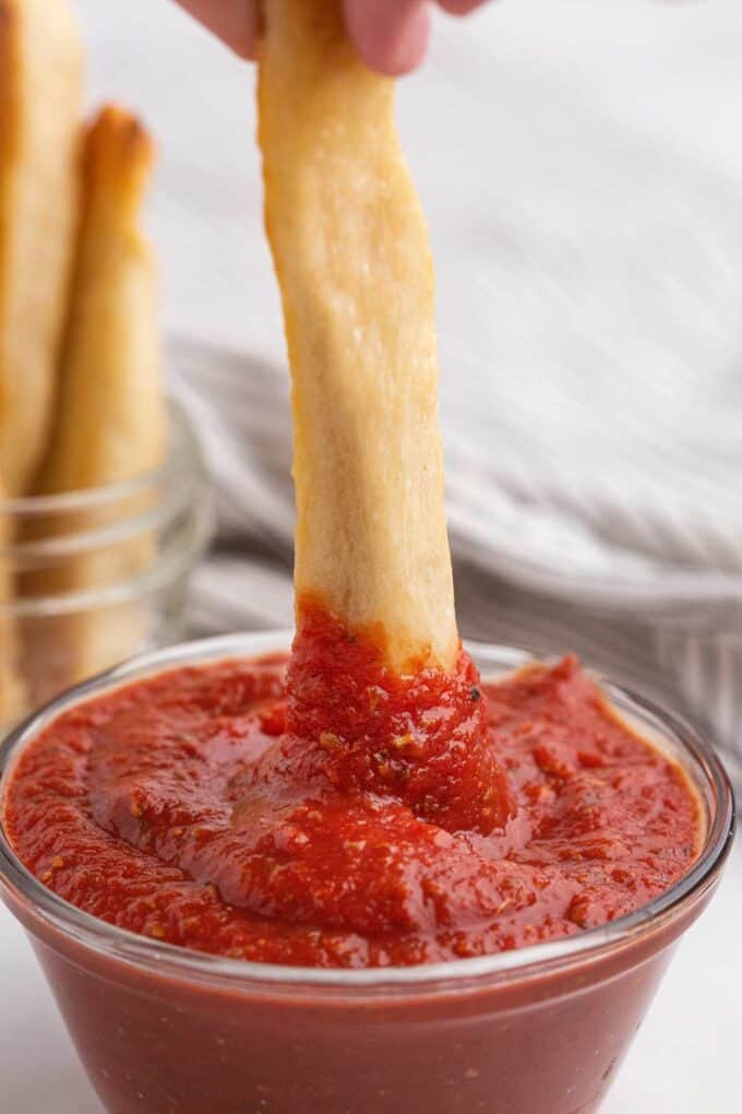 dipping breadstick into pizza sauce