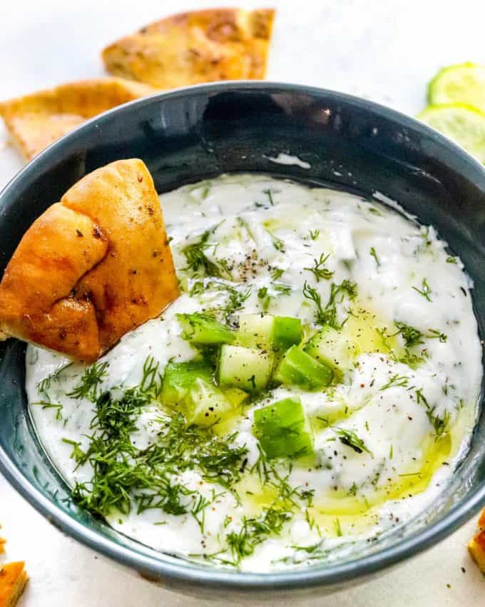 dipping pita wedge into tzatziki sauce