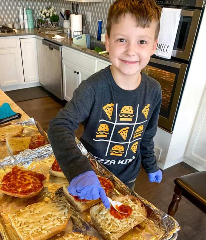 little boy making french bread pizzas