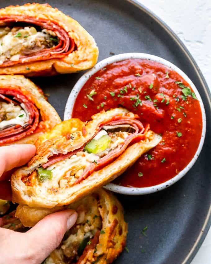 dipping a slice of stromboli into marinara sauce