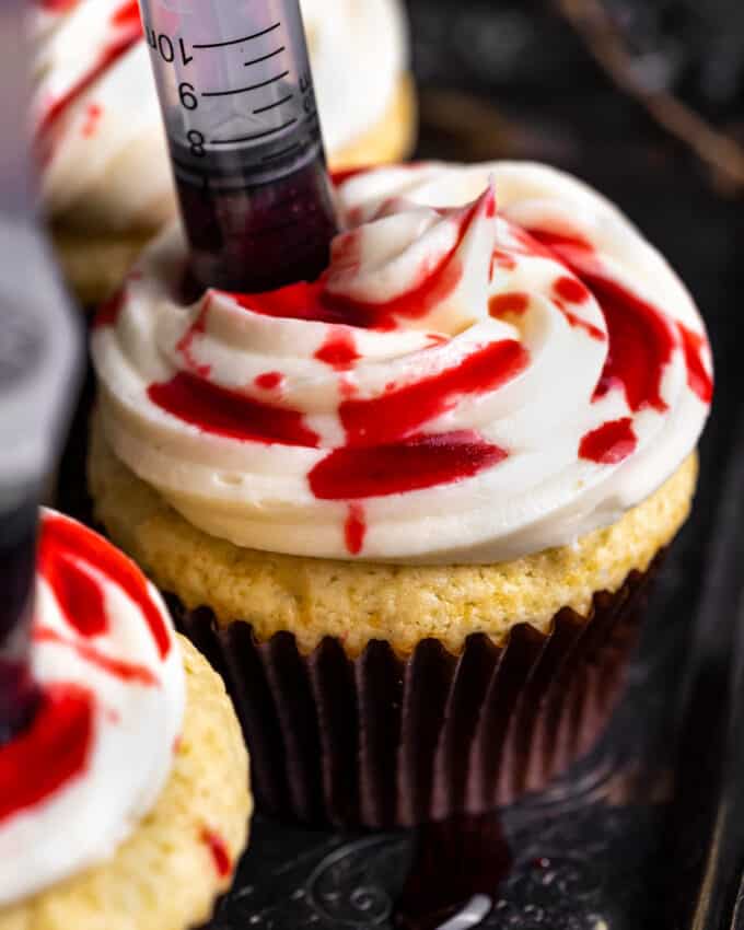 These bloody cupcakes are a delicious way to celebrate Halloween. Moist vanilla cupcakes, smooth vanilla buttercream, and the homemade fake blood really sets the spooky mood! #Halloween #cupcakes #baking