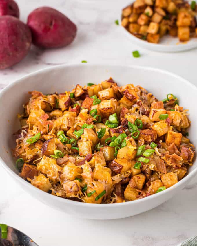 These crispy Cheesy Buffalo Roasted Potatoes are the side dish you never knew you needed in your life! Spiced potatoes, tangy hot sauce, gooey cheese, crispy bacon, fresh green onions... and top it all off with a drizzle of ranch or blue cheese dressing! #sidedish #potatoes #buffalo