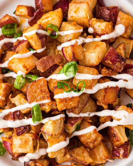 These crispy Cheesy Buffalo Roasted Potatoes are the side dish you never knew you needed in your life! Spiced potatoes, tangy hot sauce, gooey cheese, crispy bacon, fresh green onions... and top it all off with a drizzle of ranch or blue cheese dressing! #sidedish #potatoes #buffalo