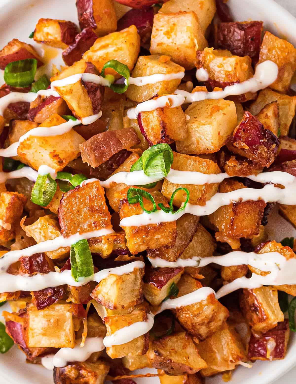 These crispy Cheesy Buffalo Roasted Potatoes are the side dish you never knew you needed in your life! Spiced potatoes, tangy hot sauce, gooey cheese, crispy bacon, fresh green onions... and top it all off with a drizzle of ranch or blue cheese dressing! #sidedish #potatoes #buffalo