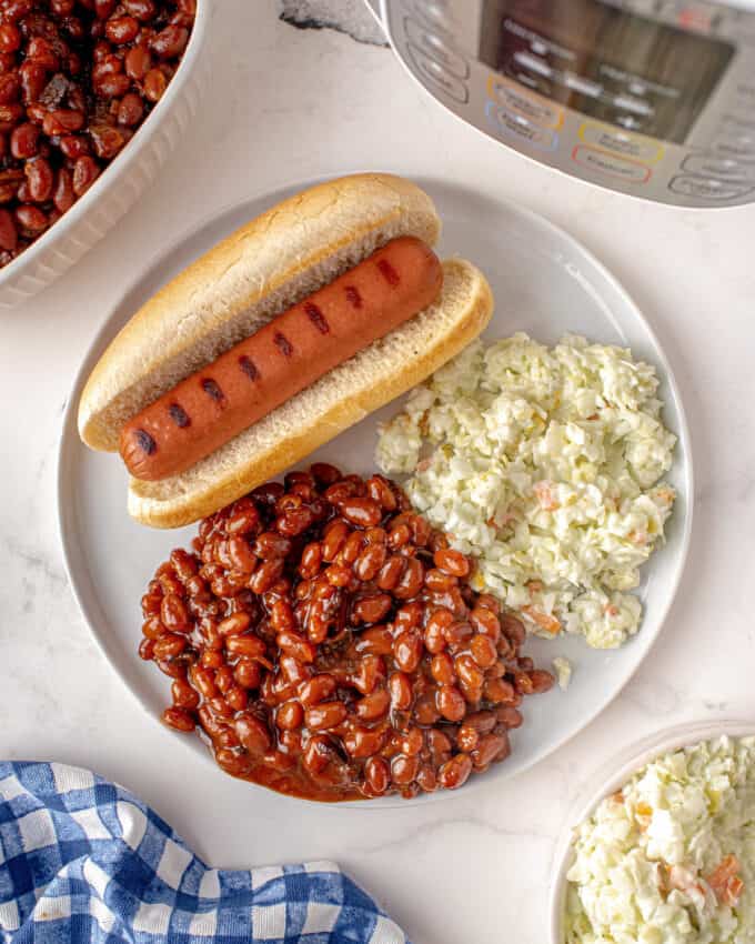 serving of baked beans on plate with hot dog and coleslaw