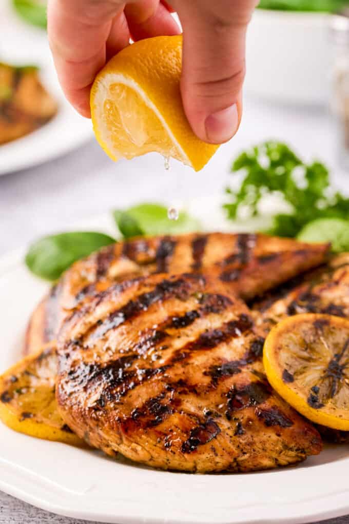 squeezing lemon over grilled chicken