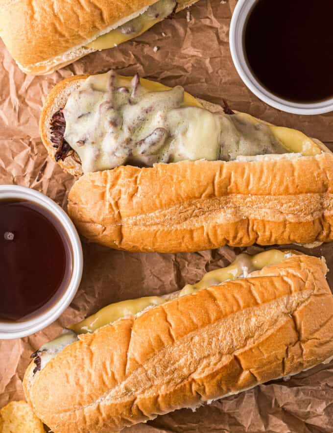 These Slow Cooker French Dip Sandwiches are made with ultra tender roasted beef, melted provolone cheese, soft hoagie bread, and dipped into an amazing au jus sauce. Perfect cold weather comfort food for the whole family! #frenchdip #sandwich #slowcooker #crockpot