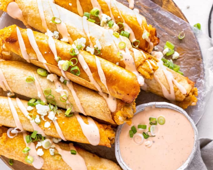 buffalo chicken taquitos on cutting board with dipping sauce