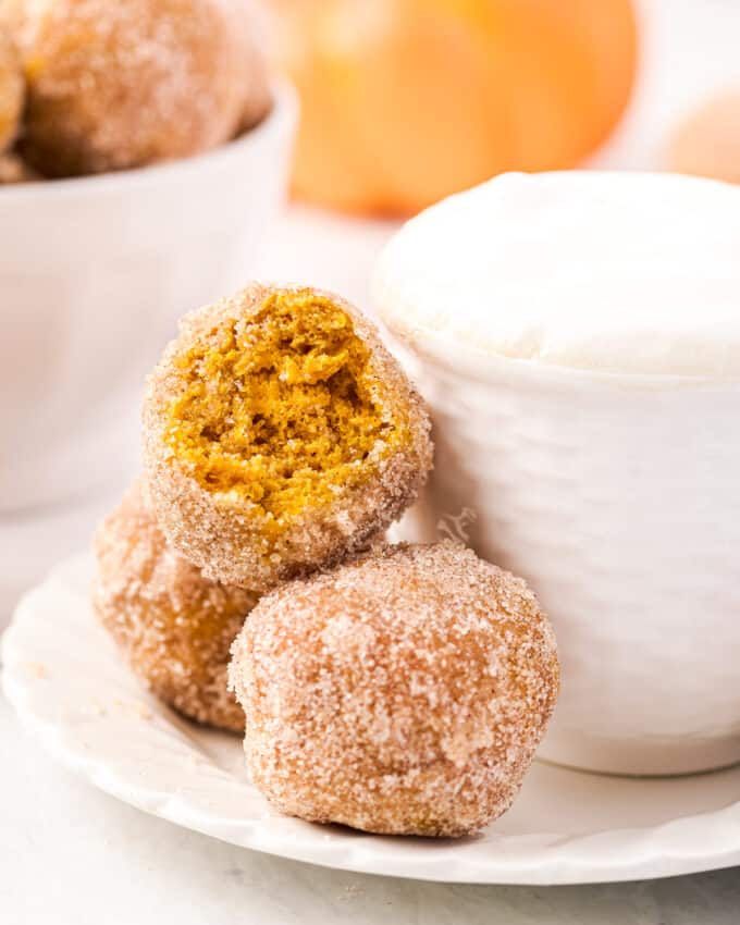 couple of donut holes on a saucer by latte