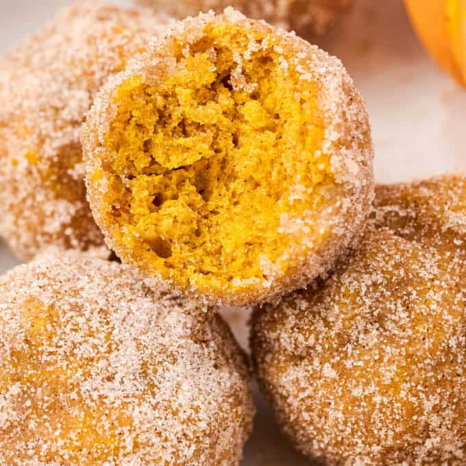 pile of pumpkin donut holes with a bite taken out of the top donut hole