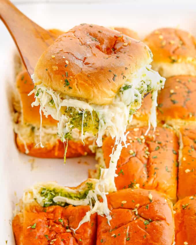 serving a pesto chicken slider with melted cheese